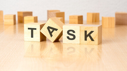four wooden blocks with text TASK on table. copy space. white background.