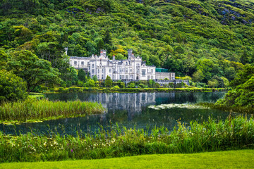 Fototapeta na wymiar Reflection of the white Kylemore Abbey and the surrounding forest during a rainy day, Connemara, Ireland