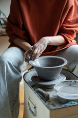 Ceramic master creating handmade stoneware on wheel in studio, making wheel-thrown ceramics, forming clay into shape. Mindful craft of pottery and art therapy concept