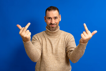 Naklejka premium Hispanic man standing over blue background showing middle finger making fuck you bad expression, provocation and rude attitude.
