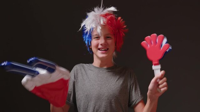 Young boy with a mohawk on his head in the color of the French flag supports his sports team. Football fan at the stadium rejoices at the victory of his team