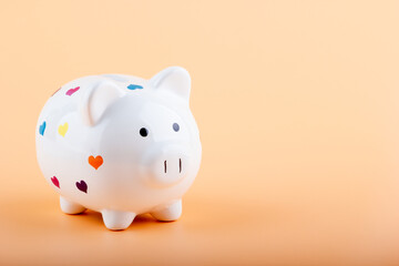 Piggy bank with multicolor hearts on a light background. Financial concept.