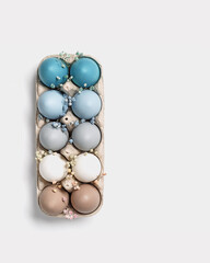 Easter eggs pastel colored in egg box decorated small flowers. Minimal Easter celebration concept, dyed chicken egg with color gradient from blue to beige coloured in carton pack. Top view