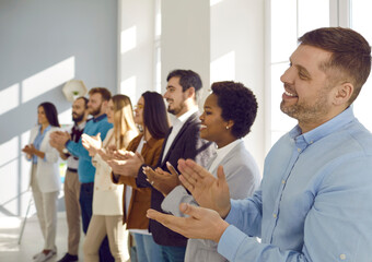 Smiling diverse businesspeople applaud thanking coach or presenter for talk or training. Happy...