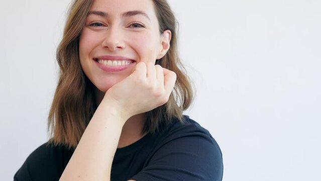 Video of happy and beautiful woman looking in camera looking naturally in black t-shirt isolated on white background.