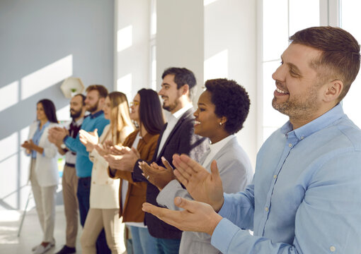 Smiling diverse businesspeople applaud thanking coach or presenter for talk or training. Happy multiethnic employees or colleagues clap hands show acknowledgement at office meeting.
