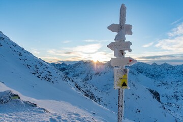 Snow covered sign marking trails on the Zawrat Pass in the winter Tatra Mountains. Winter and sunrise in Polish mountains