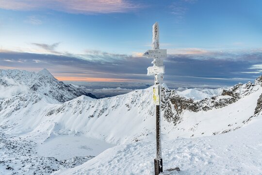 Snow covered sign marking trails on the Zawrat Pass in the winter Tatra Mountains. Winter and sunrise in Polish mountains