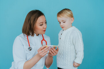 Pediatrician woman looking at thermometer with boy