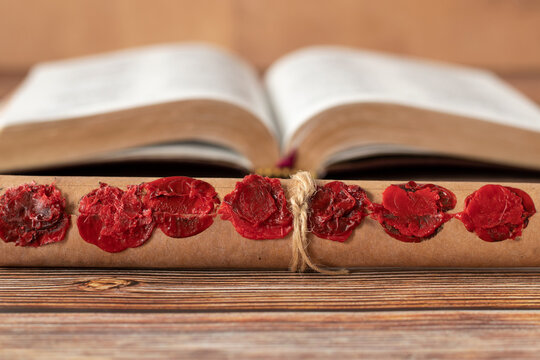 Ancient Scroll With Seven Seals In Front Of An Open Holy Bible Book. A Closeup. Christian Prophecy, Revelation, Apocalypse, Judgment Day Biblical Concept.