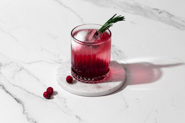 Kir Royal cocktail with cranberries and rosemary in a crystal glass on a white background