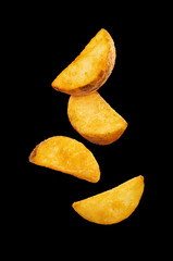 Flying fried potato wedges, isolated on black background