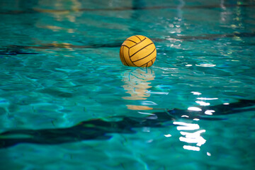 Yellow water polo ball in a swimming pool on blue water background. Film noise and gain - 558485959