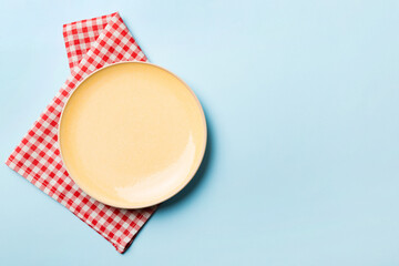 Top view on colored background empty round yellow plate on tablecloth for food. Empty dish on...