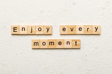 Enjoy Every Moment word written on wood block. Enjoy Every Moment text on cement table for your desing, concept