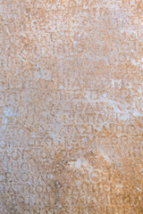 Fragment of ancient greek inscription, carved on marble block at the archaeological site of Ephesus. Selcuk, Turkey (Turkiye). Selected focus. Ancient art and history concept. Retro background