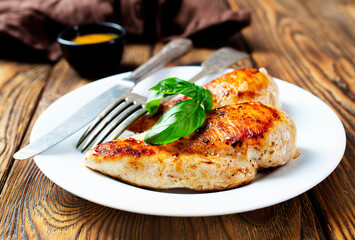 Marinated grilled healthy chicken breasts cooked on a summer BBQ and served with fresh herbs and lemon juice