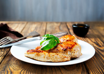 Marinated grilled healthy chicken breasts cooked on a summer BBQ and served with fresh herbs and...