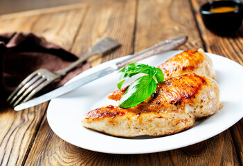 Marinated grilled healthy chicken breasts cooked on a summer BBQ and served with fresh herbs and lemon juice