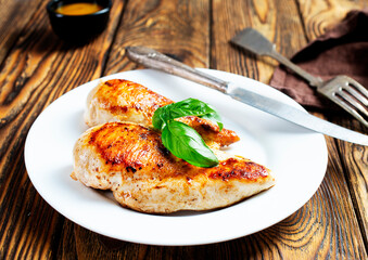 Marinated grilled healthy chicken breasts cooked on a summer BBQ and served with fresh herbs and...