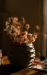 backlited flowers in vase on the table in sunset time