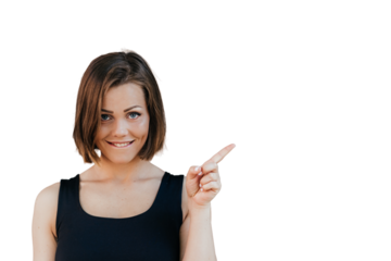 Happy fitness beautiful girl with short hair dressed casual, pointing at the free space with her index finger, looks satisfied over transparent background. Happy people concept