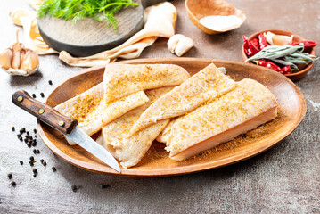 Fresh raw fish fillet with spices, pepper, salt, basil on a stone plate, top view, square