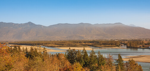 Sunny autumn landscape. Morning sunlight on valley with river and mountains. Sunny autumn lanscape during sunset