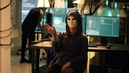 Female hacker with anonymous mask using hologram to break into firewall encryption, holographic...