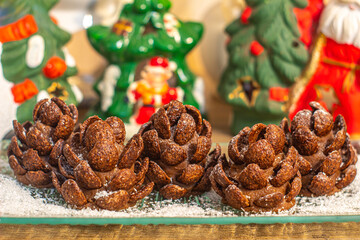 Dark Chocolate realistic edible Pinecone cake sprinkled with powdered sugar and coconut flour as snow. Cool-looking Christmas cookies on plate macro.