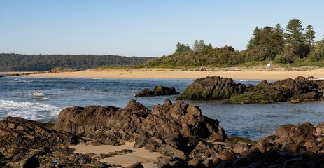 View of One Tree Beach from One Tree Point in Tuross Head on the south coast of New South Wales, Australia. Early morning light. Rocks in foreground