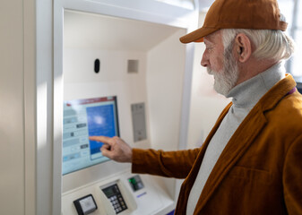 Senior man using ticket machine on train station