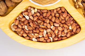 Peanuts, walnuts and hazelnuts in a wooden box with compartments. Three different types of nuts, shelled and shelled, decorative assortment and ready to eat. Closeup, isolated, from above.