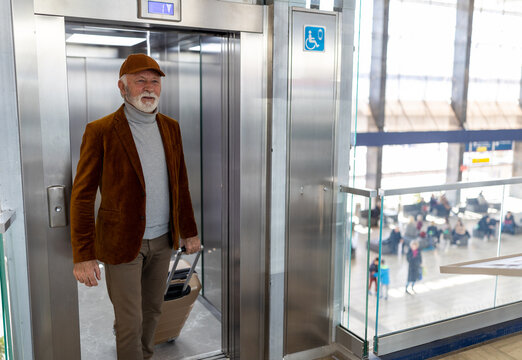 Man with suitcase using elevator on train station