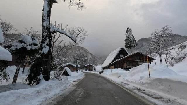 Driving by snow covered houses in traditional Japanese mountain village