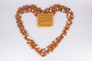 Obraz premium Homemade peanut butter and patterned sandwich isolated on white background. The concept of love for nuts. Favorite breakfast. Nuts in the shape of a heart.