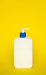 Square white blank unbranded cosmetic plastic bottle with dispenser pump for shampoo, gel, lotion, cream, bath foam on yellow background.