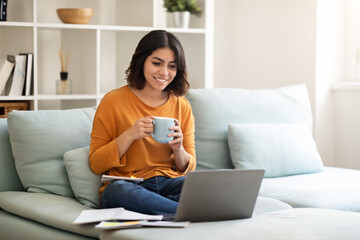 Smiling Arab Female Study With Laptop And Drinking Coffee At Home
