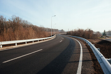 Fototapeta premium New asphalt road with markings and road signs in the sun's rays