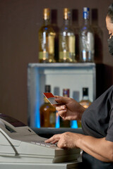 woman working at cash register typing code. cashier in a disco bar, with a credit card in her hand, making data entry