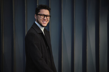 The smiling Asian guy in glasses and a business suit, walking