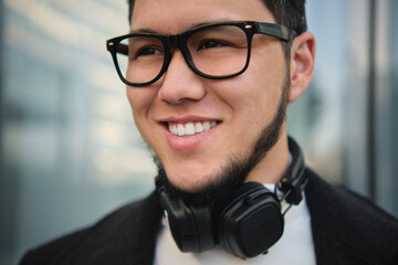 An Asian guy businessman in a headphones closeup shot, outdoor
