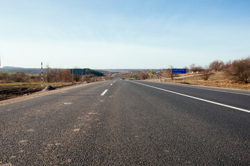 New asphalt road with markings and road signs in the sun's rays