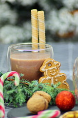 A cup of hot chocolate, waffles and a gingerbread man will warm you up during the cold winter season. The composition is complemented by a pine branch, sweets and a warm atmosphere