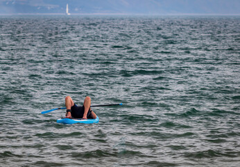 man lying on a paddle board at Weymouth beach front England