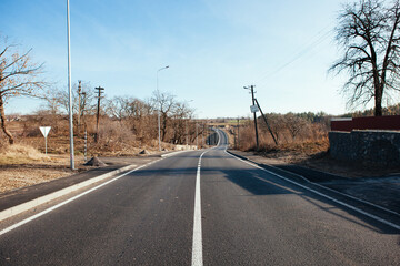 New asphalt road with markings and road signs in the sun's rays