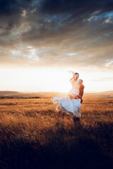 The bride and groom hold hands and look to the future in the middle of nature, the newlyweds walk together,wedding photography,until death do us part