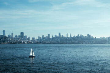 San francisco skyline on a muggy day with a sailboat sailing through the waves