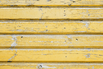 Old peeling paint texture. Grunge cracked wooden wall background. Yellow color weathered surface. Broken wood desk structure. Vintage board pattern design.