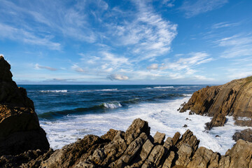 Sea waves crash against stones in beautiful white splashes. Seascape. Panoramic view of the seashore
